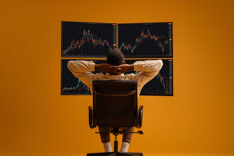 גבר נשען לאחור בכיסא מנהלים ומביט במסכים עם גרפים