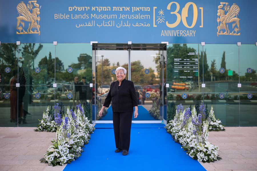 בתיה בורובסקי על שטיח כחול בפתח מוזיאון ארצות המקרא ירושלים
