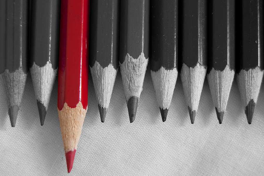 קבוצת עפרונות שחורים ואחד אדום בולט קדימה
