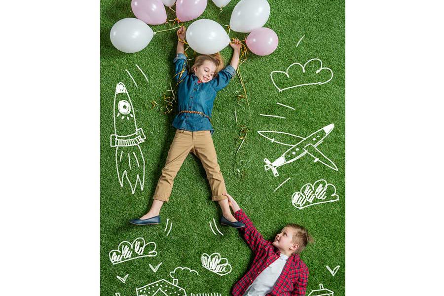 שני ילדים שוכבים על דשא עם בלונים