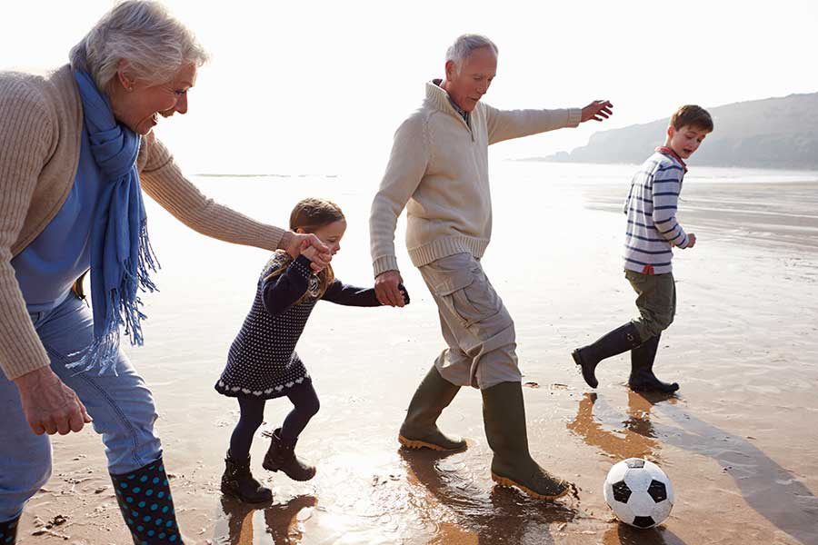סבים ונכדים משחקים בכדור בחוף הים