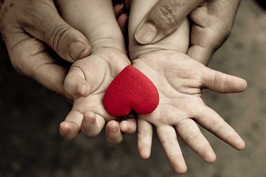 ידי אבא מחזיקות יחד עם ידי ילד לב אדום