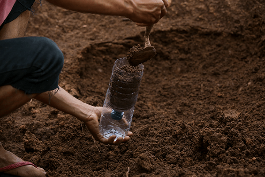 אדם ממלא אדמה בבקבוק פלסטיק