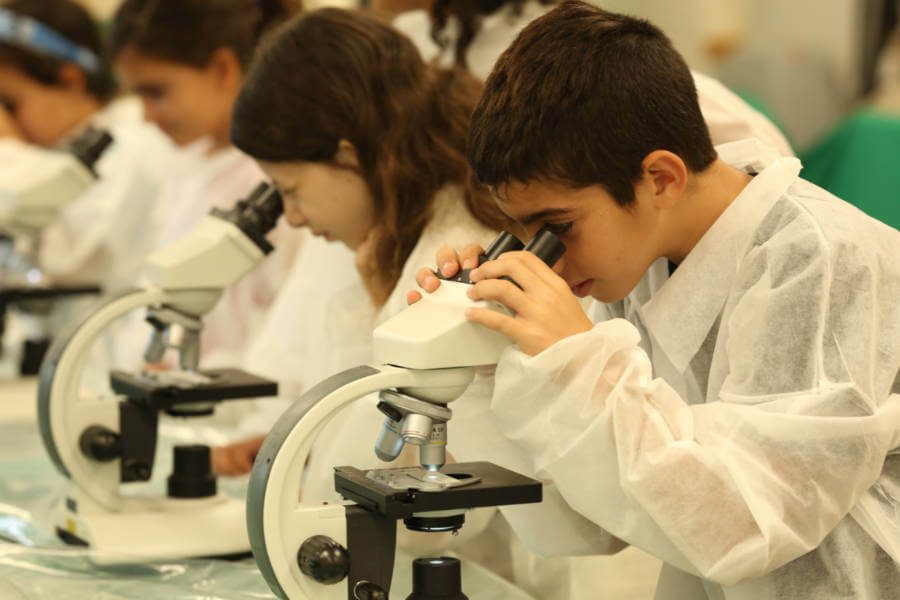 ילדים בחךוקים לבנים מביטים דרך מיקרוסקופ