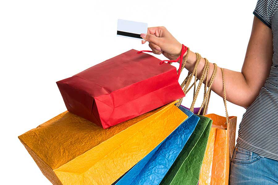 יד אישה מחזיקה שקיות קניות צבעוניות
