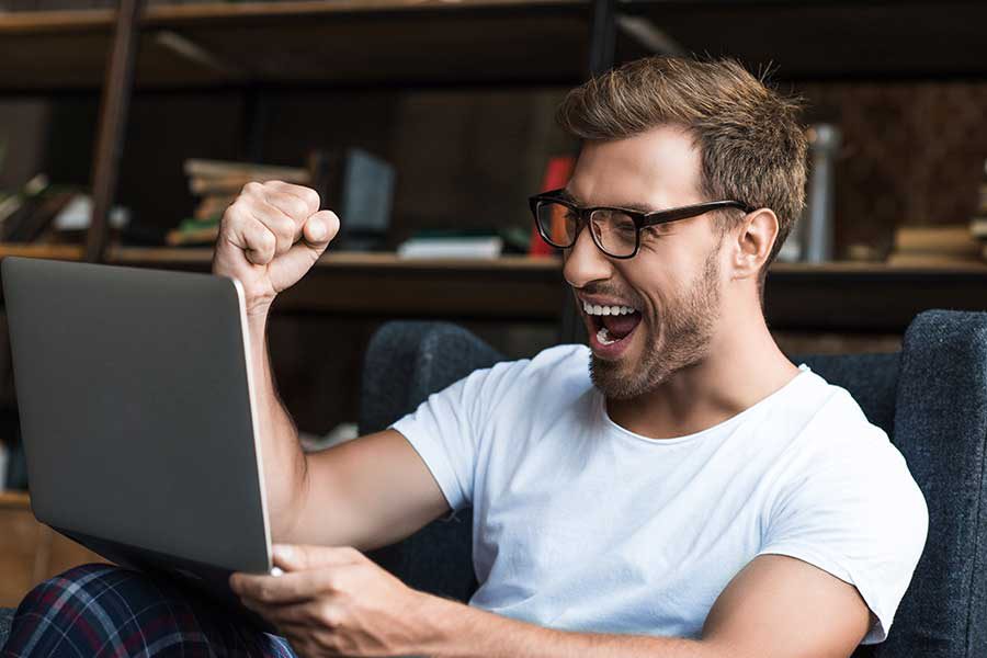 גבר מאושר מביט במסך מחשב
