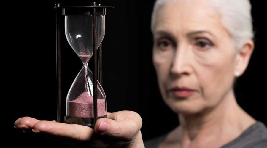 אישה מחזיקה שעון חול על כף ידה