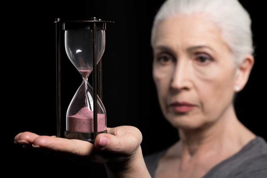 אישה מחזיקה שעון חול על כף ידה