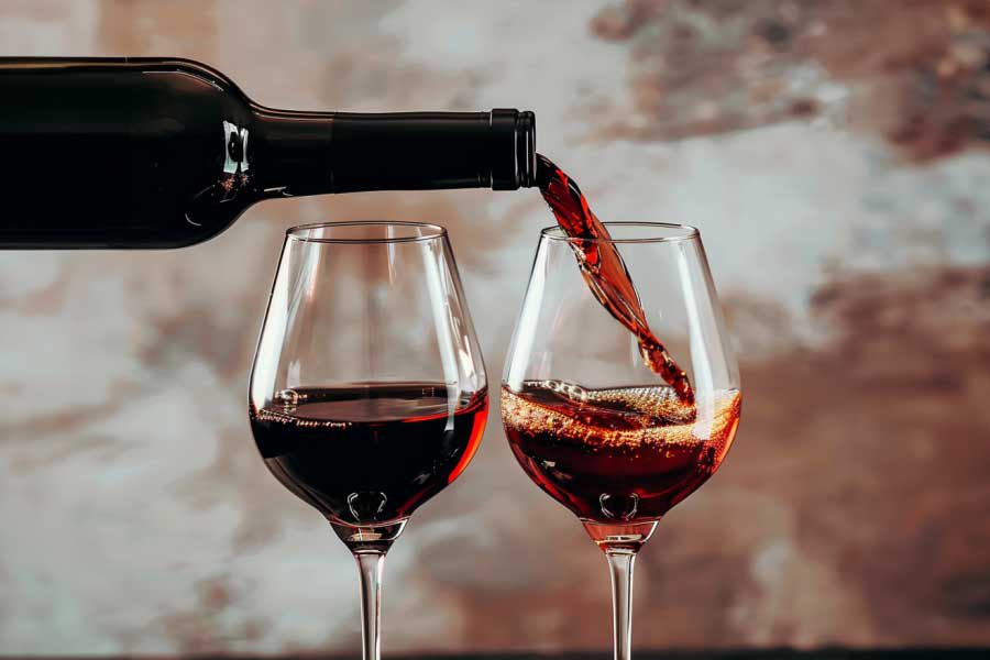 בקבוק יין אדום מוזג לשתי כוסות