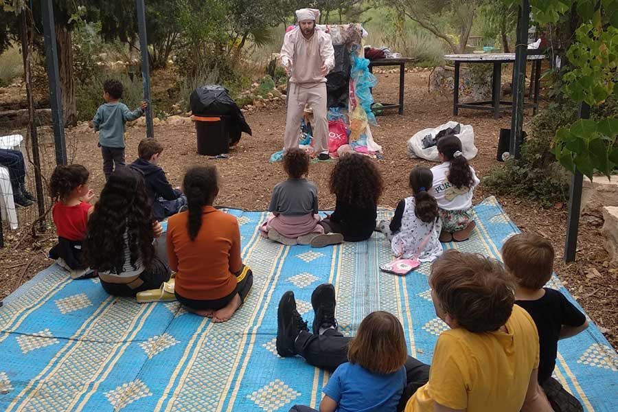 ילדים על מחצלת ומולים מופיע שחקן מחופש