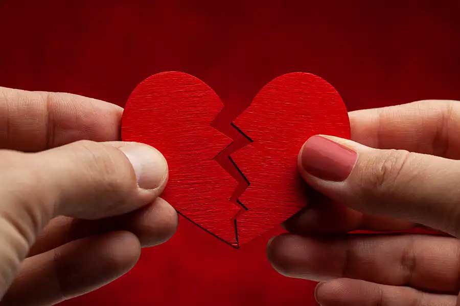 ידי גבר ואישה מחזיקים לב אדום מנייר